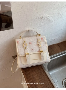 Close-up of cream faux leather backpack featuring cute cat patterns and gold buckle details