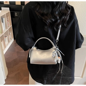 Detailed view of silver metallic crescent bag with white horse charm on a model
