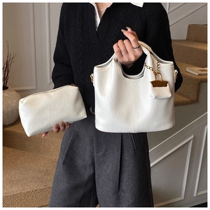 Détail du sac fourre-tout crème avec breloque dorée et pochette zippée assortie