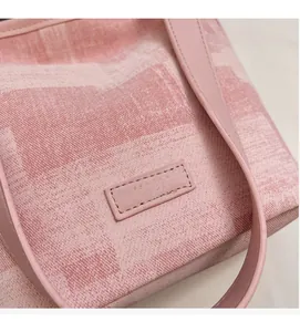 Dettaglio della borsa a secchiello rosa con manico in pelle e logo dorato in rilievo