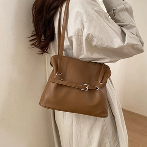 Close-up of brown pleated tote bag featuring decorative belt strap and silver buckle
