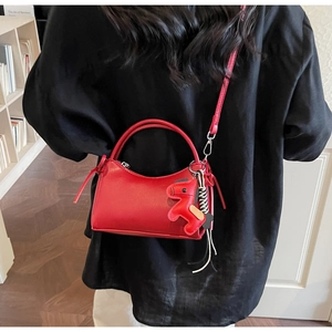 Rear view of a red PU leather handbag with horse charm and slim shoulder strap