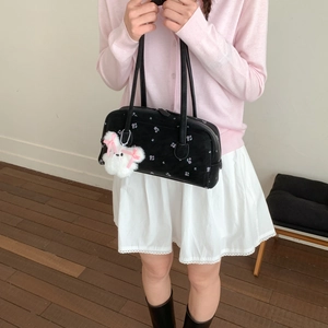 Close-up of black shoulder bag with purple floral pattern and plush rabbit charm