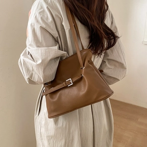 Detailed view of a brown vintage tote bag with pleated leather texture worn by a model