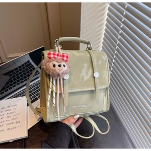 Detail view of sage green faux leather backpack with plush keychain and metal buckle