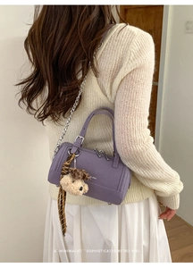 Détail du sac à main cylindrique violet en cuir avec chaîne argentée et foulard en soie