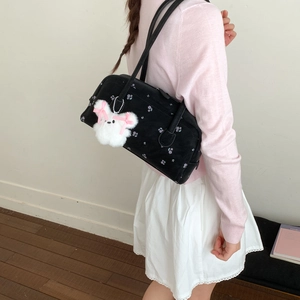 Model wearing a black nylon shoulder bag with purple floral print and plush rabbit charm