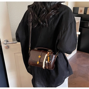 Detail view of vintage brown crossbody bag with decorative tricolor beads and gold buckle