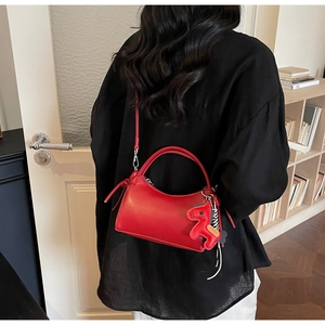 Detail view of red leather handbag with horse charm accessory and silver hardware detail