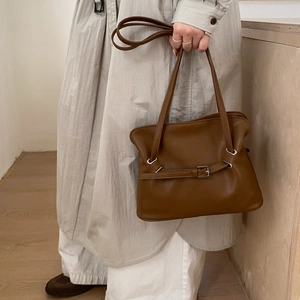Detailed view of brown leather tote bag with metallic buckle and smooth texture finish