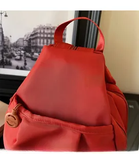 Dettaglio della trama del zaino in tessuto Oxford rosso con ciondolo decorativo rotondo