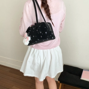 Close-up of black floral shoulder bag with a cute white rabbit keychain and metal zipper
