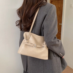 Close-up of beige vintage tote bag with buckle detail worn with grey blazer suit