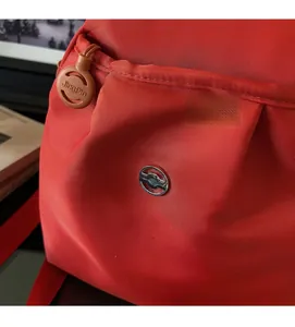 Dettaglio dello zaino rosso in tessuto oxford con trama twill e logo in argento