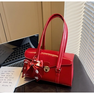 Détail d'un sac à main rouge brillant avec foulard en soie et fermoir métallique chic