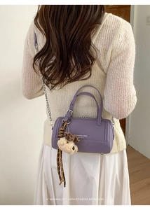 Détail du sac cylindrique violet avec breloque chien peluche et chaîne en métal