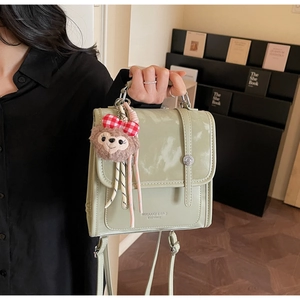 Detail of light green vintage faux leather backpack with plush bear charm on side
