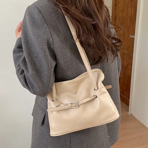Detail of beige pleated tote bag with buckle strap on a grey blazer outfit