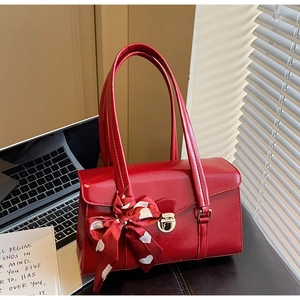 Détail du sac de mariage en cuir rouge avec foulard à cœurs et fermoir doré en métal