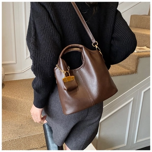 Détail du sac cabas en cuir marron foncé avec un mini sac décoratif et une boucle en métal