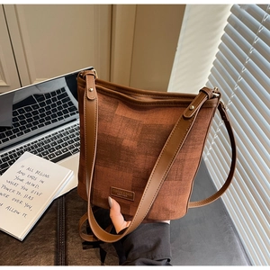 Dettaglio della borsa a secchiello in tela marrone con finiture in pelle e logo alla moda