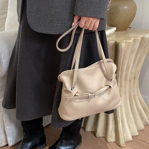 Detail showing beige pleated tote bag with buckle straps and silver eyelets for work