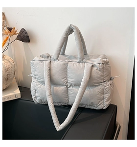 Detailansicht der hellgrauen gesteppten Puffer-Tasche mit Kordelzug und Trageriemen