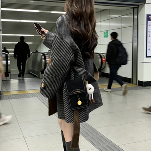 Detail of black matte leather mobile phone crossbody bag with gold buckle and plush charm