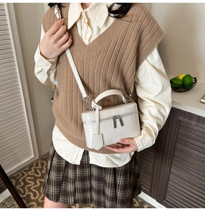 Detail of cream vanity box bag with silver hardware and adjustable leather strap