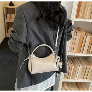 Chic cream white crossbody bag with horse charm shown in a minimalist lifestyle setting