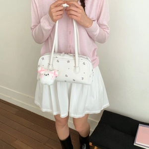 Floral print shoulder bag with plush puppy pendant and long straps on a model