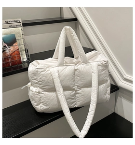 Detailansicht der weißen gesteppten Puffer-Tasche mit seitlichem Kordelzug und langem Gurt