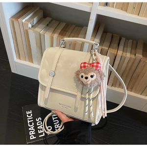 Detail view of cream vintage backpack featuring a Duffy bear plush charm on the side