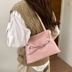 Pink matte leather tote bag with eyelet details shown worn on a model's shoulder