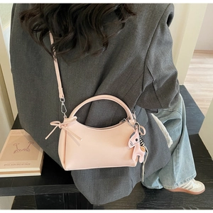 Detailed view of pink crescent handbag with leather pony charm and slim bow ties