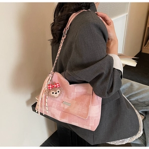 Dettaglio della borsa a tracolla in tela scozzese rosa con catena e ciondolo plush