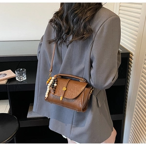 Brown vintage pleated leather crossbody bag with wooden bead charm detail on model