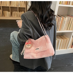 Borsa a tracolla rosa a scacchi con catena e ciondolo di peluche in una biblioteca