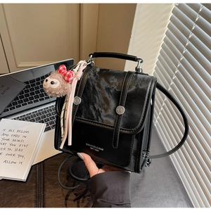 Detail of vintage black leather backpack with monkey pendant and MIKAXIQI branding