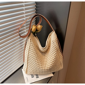 Close-up of woven cream tote bag with brown leather strap and hollow crochet texture