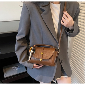 Detail of vintage brown shoulder bag with colorful bead charm and oil wax leather texture