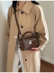 Detailed view of dark brown vanity box bag with silver zippers and elegant leather top handle