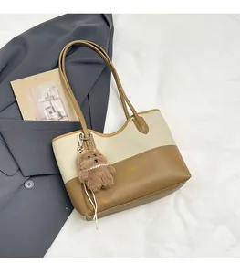 Dettaglio della borsa tote in tela con finiture in pelle, logo dorato e ciondolo