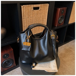 Détail du sac à main en cuir noir avec une chaîne dorée et un mini pendentif de sac