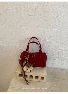 Détail du sac à main Boston rouge en daim avec double fermeture éclair et pompon ours