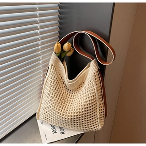 Detail of cream woven tote bag showing crochet texture and brown leather straps