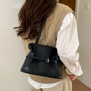 Detail view of black pleated tote bag showing soft leather texture and silver buckle