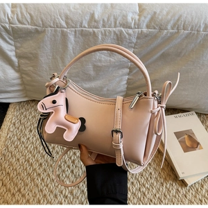 Close-up of pink crescent handbag featuring leather pony charm and elegant bow detail