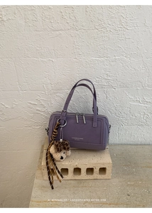 Détail du sac à main lilas en cuir avec breloque ours en peluche et foulard décoratif