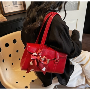 Détail d'un sac à main de mariée en cuir verni rouge avec un nœud en soie à motifs cœurs